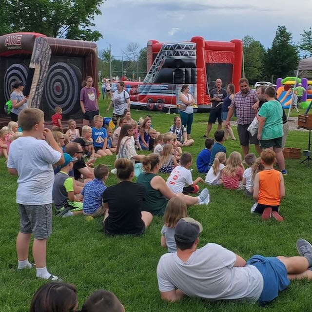 A park crowd of seated children watching the stage show